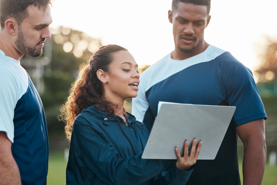 Un homme sur un terrain de foot, assis devant un ordinateur portable