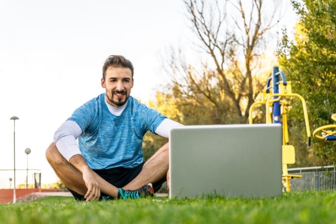 Un homme sur un terrain de foot, assis devant un ordinateur portable